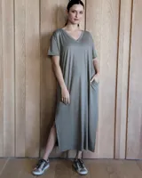 Vestido midi de corte holgado y estilo casual, confeccionado en tejido acanalado de color verde oliva. Presenta escote en V, mangas cortas y aberturas laterales en el ruedo, además de bolsillos laterales.