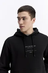 Canguro oversize de algodón, color negro, con capucha ajustable, bolsillo frontal tipo canguro y estampa sutil en el pecho.