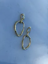 Aros colgantes de diseño artesanal con eslabones irregulares de textura orgánica y acabado en tono dorado.