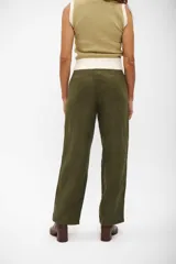Pantalon de corte recto y tiro alto en color verde oliva, confeccionado en tejido con textura similar a la gamuza. Presenta costuras horizontales a la altura de las rodillas y cierre frontal con botón oculto.