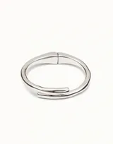 Pulsera rígida de diseño tubular con acabado plateado, fabricada en una aleación de metales bañados en plata. Presenta un diseño de extremos superpuestos y un cierre de muelle oculto.