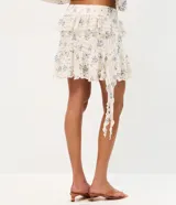 Pollera corta evasé de encaje floral Liberty, con volados asimétricos en capas y forro interno.