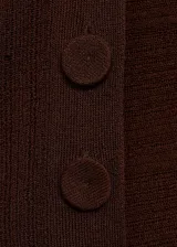 Buzo de tejido de punto fino color marrón, con cuello perkins, manga larga y diseño semitransparente. Presenta un corte asimétrico con abertura lateral y detalle de botones.