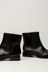 Bota corta de cuero metalizado en tono plateado con efecto arrugado, de caña media, punta fina y taco bajo cuadrado.