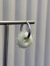 Aros tipo argolla con dije de vidrio en forma de dona color blanco, con textura de pequeñas esferas de vidrio alrededor. Base de plata 925.