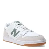 Championes New Balance modelo 480 Court de estilo retro inspirado en el básquet. Presentan un diseño en color blanco con detalles en verde oliva en el logo lateral y la lengüeta, puntera y talón en gamuza color beige, y suela de goma color caramelo.