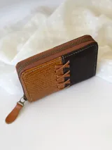 Billetera pequeña de cuero marrón y negro con cierre metálico y monedero interno.