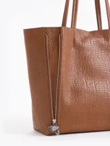 Cartera tipo shopper de cuero vacuno flor graneado, con formato amplio y estructura flexible. Presenta dos cierres verticales decorativos en el frente con tiracierres personalizados y doble manija de hombro.