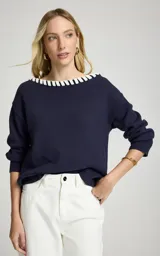 Sweater azul marino de tejido de punto con escote barco, detalle contrastante en color blanco a lo largo del borde, mangas largas con hombros caídos y ajuste ligeramente holgado.