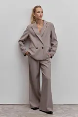 Blazer de corte sastrero con diseño cruzado y cierre de doble botonadura frontal. Presenta solapas clásicas y bolsillos laterales con solapa, confeccionado en tela con estampado de cuadros pequeños.