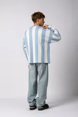 Sweater de tejido de punto con diseño a rayas verticales en color celeste y blanco. Presenta un corte holgado, cuello redondo y detalles gráficos en negro en el frente, incluyendo la palabra 'Argentina' y estrellas bordadas.