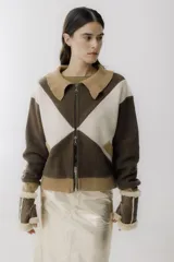 Chaqueta bomber azul marino con paneles color mostaza en forma de rombos. Tiene cuello tipo camisa, cierre frontal con cremallera, bolsillos de parche y puños y bajo acanalados en color marrón.