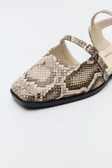 Zuecos destalonados color crema, de símil cuero, con punta cuadrada y finas tiras con hebillas ajustables. Cuentan con taco de 2,5cm de alto.