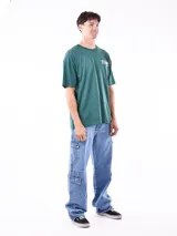 Remera negra de corte oversize con cuello redondo y manga corta. Presenta un pequeño estampado en el pecho con texto en color verde azulado.