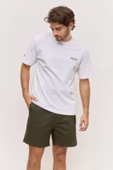 Remera blanca de algodón, de corte holgado y mangas cortas, con pequeño estampado azul en el pecho.