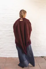 Ruana de lana color negro con terminación de flecos en los bordes y diseño con caída en picos en la espalda.