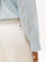 Pantalón estilo sastre, color blanco, confeccionado en piqué de mezcla de algodón y nylon. Presenta costura marcada en la parte delantera, cintura elástica y logo de Tommy Hilfiger bordado en fuente script en la pierna.