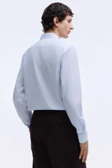 Camisa de corte entallado con cuello inglés, canesú en la espalda y mangas largas con puños ajustables. Presenta un diseño de rayas verticales finas y un bajo levemente redondeado.