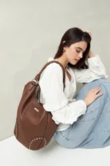 Bolso shopper marrón de símil cuero texturizado con asas cortas y detalles de tachas metálicas.