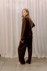 Pijama de tela velvet color gris oscuro, compuesto por una camisa de manga larga con botones y vivo en contraste rojo, y un pantalón recto con elástico en la cintura.