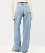 Pantalón wide leg de tiro bajo confeccionado en jean de algodón, con cierre frontal y aplicación de brillos y tachas en los laterales.