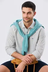 Camisa de manga larga de lino y algodón, con diseño de rayas verticales en tonos celestes y blancos. Presenta cuello camisero, cierre frontal con botones y pequeño bordado al tono en el pecho.
