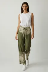 Pantalón de viscosa holgado, tiro alto, color verde oliva con estampado en beige que simula un sol o abanico en la cintura y los puños. Posee lazo para atar en la cintura.