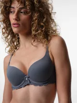 Soutien con copa preformada y aro, confeccionado en microfibra lisa color gris azulado. Presenta detalles de encaje en la base y un pequeño lazo decorativo con dije en el centro. Cuenta con breteles ajustables y cierre posterior con broche.