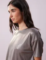 Blusa gris metalizada de tejido lurex, marca June & Hudson, con cuello redondo y ruedo con nudo en la espalda.