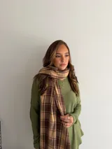 Bufanda de tejido suave con diseño de cuadros grandes en tonos negro y beige, terminada con flecos en los extremos.