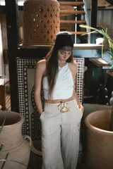 Pantalón de corte recto y tiro alto, confeccionado en lino color blanco. Presenta cierre frontal con botón y bolsillos laterales.