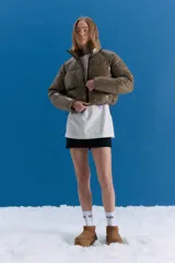 Campera puffer corta a la cintura, color verde militar con acabado brillante. Presenta cuello alto, cierre frontal completo y bolsillos laterales con cierre invisible.