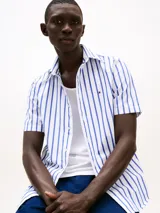 Camisa de manga corta Tommy Hilfiger, corte regular, confeccionada en popelín de algodón con tecnología Flex. Diseño a rayas verticales blancas y azules.