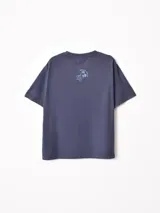 Remera de manga larga con diseño superpuesto que simula una camisa de rayas debajo. La prenda principal es de color azul piedra con estampado gráfico de Minnie Mouse y texto alusivo al tenis, mientras que las mangas y el cuello son de tela camisera a rayas celestes y blancas.