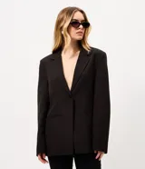 Blazer de sastrería negro de corte oversize, con solapas clásicas, cierre frontal de un botón y bolsillos con solapa.