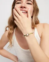 Pulsera de hilo verde oscuro con dije central de perla shell y fornitura bañada en plata de ley.