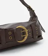 Cartera tipo baguette mediana en PU color marrón, con diseño alargado y asa corta para el hombro. Presenta un detalle frontal de cinturón con hebilla metálica y ojalillos.