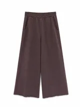 Pantalon de estilo deportivo confeccionado en tejido de punto, color marrón. Presenta un corte amplio de pierna ancha, cintura elástica con cordón interno, bolsillos laterales y terminación de ruedo desflecado.