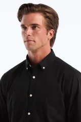 Camisa de hombre negra de popelina elástica, con cuello abotonado, manga larga y bolsillo en el pecho.