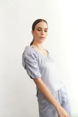 Blusa negra de seda con escote en V y mangas abullonadas cortas. Tiene cierre lateral.