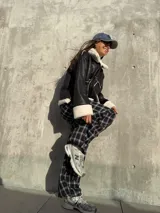 Campera tipo gamulán de cuero sintético negro con interior y detalles de corderito blanco. Presenta cierre frontal, bolsillos laterales y diseño holgado.
