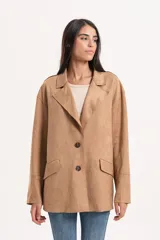 Blazer de estilo oversize confeccionado en material simil gamuza, con cuello solapa, cierre frontal de dos botones y bolsillos laterales con solapa.