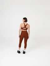 Calza deportiva tipo crop, de tiro alto y ajuste ceñido, confeccionada en tejido elástico de color marrón.