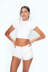 Remera deportiva blanca de corte crop top, confeccionada en tejido de punto suave al tacto.