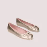 Bailarinas doradas de cuero con lazo decorativo en la puntera y plantilla de color rosa.