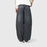 Pantalón de jean estilo ultra baggy, color negro lavado, con diseño de paneles curvos y costuras reforzadas en las piernas. Presenta un corte extremadamente holgado y tiro medio.