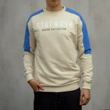 Buzo color arena con mangas ranglan azul eléctrico y estampa frontal con la palabra "Strength" y la frase "Duxon Collection".