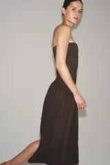 Vestido midi de corte bandeau con escote palabra de honor y detalle de vuelta en el pecho. Presenta una cintura entallada con pliegues y una falda con volumen en tejido combinado a tono.