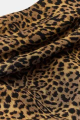 Pañuelo tipo pareo con estampado animal print, confeccionado en viscosa. Presenta un diseño triangular con cierre mediante arandelas metálicas y mosquetón.