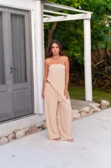 Pantalón de corte amplio y tiro medio, confeccionado en tela crepe color beige, con diseño fluido y holgado.